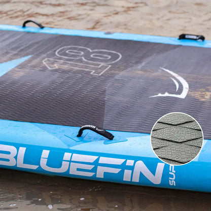 Inflatable paddleboard with textured deck pad, blue edges, and center fin on wet sand
